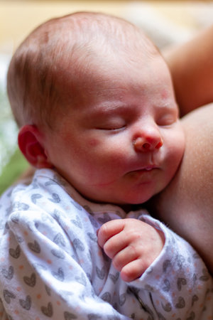 Newborn baby girl sleeping peacefully in her mother's arms, close upの写真素材