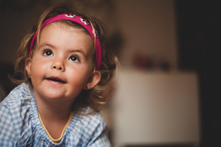 Portrait of cute little girl with curly hair in a blue shirtの写真素材