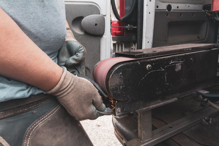 Worker cutting metal with electric grinder, close-up.