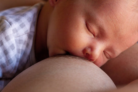 Newborn baby boy sleeping in his mother's arms, close upの写真素材