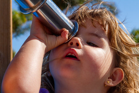 A young girl gazing through a telescope, capturing the innocence and joy of childhood imagination.