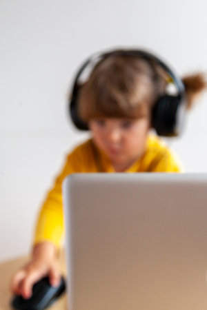 Blurred image of a boy in headphones using a laptop at homeの写真素材