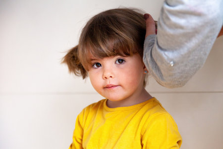 Cute little girl with blonde hair and blue eyes in yellow t-shirtの写真素材