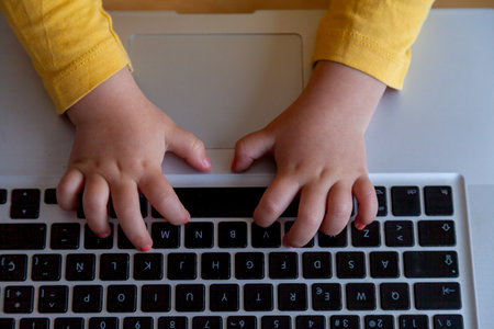 Close up of a real child's hands typing on a laptop keyboard.の写真素材
