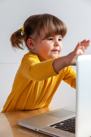 Real Cute little girl using a laptop computer at home. Technology concept.の写真素材