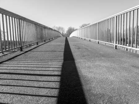 Bridge over a river, with the railing as a shadow in the middle. in black and whiteの写真素材
