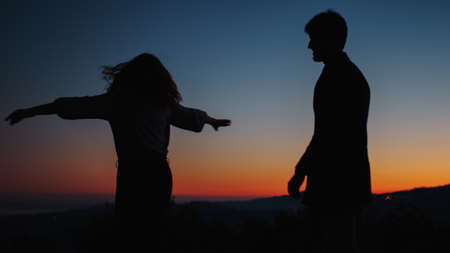 Silhouette of boy and girl while dancing happyの写真素材