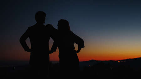Silhouette of boy and girl hug each other at sunsetの写真素材