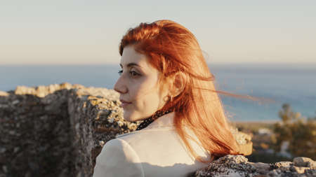 Beautiful girl with white dress explores an ancient Italian castle at sunsetの写真素材