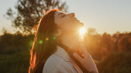 Beautiful girl in the countryside in front of the setting sunの写真素材