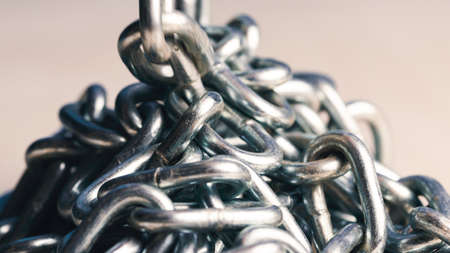 Metal iron chain slowly falls on a wooden tableの写真素材