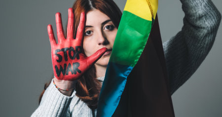 Girl wrapped in the peace flag raises her red hand that says stop warの写真素材
