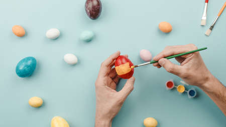 Hand of a man is painting colored Easter eggsの写真素材