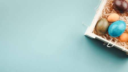 hand of a man is placing Easter colored eggs on the boxの写真素材