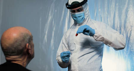 Doctor is making the swab test on the noise of the patient with covid suitの写真素材