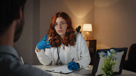 Italian Female doctor and patient behind anonymous man in private clinicの写真素材