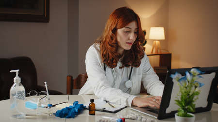 Young beautiful Italian female doctor writes the prescription on the laptopの写真素材