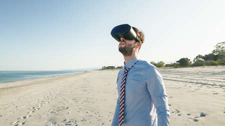 Business man in blue shirt wears virtual reality glasses at the beachの写真素材