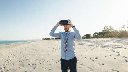 Business man in shirt wears virtual reality glasses at the beach