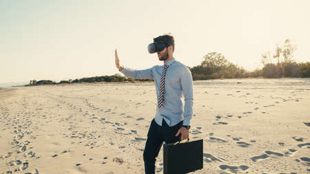 Business boy with virtual reality headset walks at the beach near the seaの写真素材