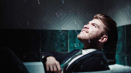 Young businessman in the bathtub plays with soap bubblesの写真素材