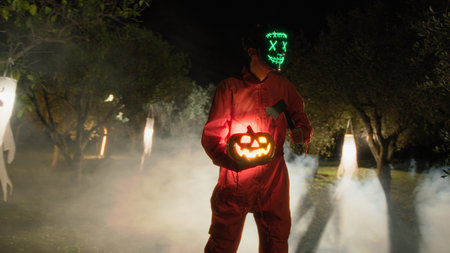 Anonymous Man in Glowing Mask with Halloween Pumpkin And Axe