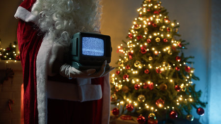 Santa Claus Holds A Vintage Television With Static Signal In Front Of Treeの写真素材