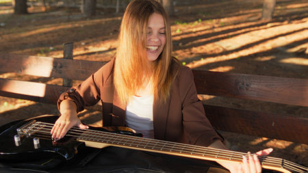 Happy Girl Playing Bass Instrument In The Park On The Table