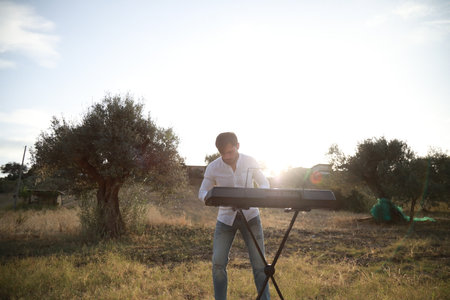 Man Plays The Musical Keyboard In The Countryside In Calabria Among Olive Treesの写真素材