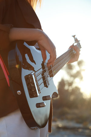 Girl Plays Bass Music Instrument On The Beach At Sunset Near Ocean