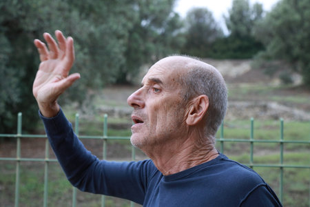 Elderly Man Waving His Hand To Call His Friends Who Cant See Him From Distance