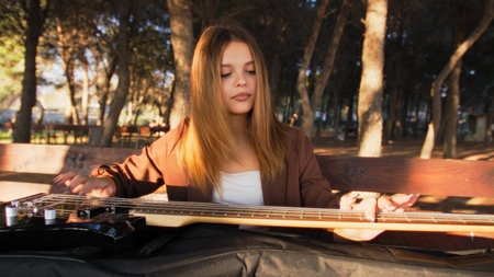 Girl Plays Bass Musical Instrument Sitting In The Mountain Forestの写真素材