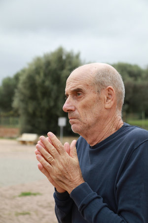 Elderly Man Tries to Take Shelter Under a Tree in Winterの写真素材