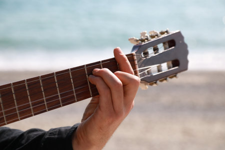 Hand Of A Man Plays Classical Guitar On The Beach Near The Sea In Summer