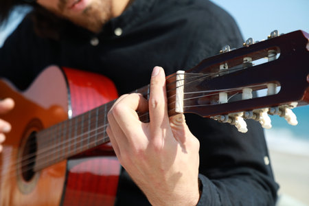 Man Plays Classical Guitar On The Beach Near The Sea In Summerの写真素材