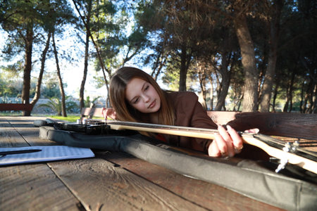 Girl Plays Bass Musical Instrument Sitting In Table In The Mountain Forest