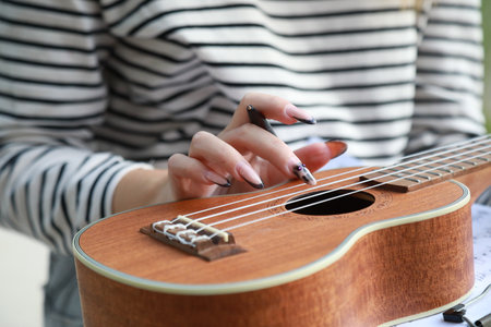 Girl Writes Notes On A Sheet Music To Play Them With The Ukuleleの写真素材