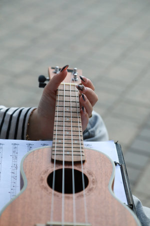 Girl Writes Notes On A Sheet Music To Play Them With The Ukuleleの写真素材
