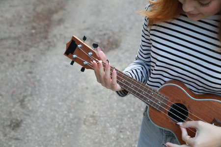 Girl Strums With Ukulele Musical Instrument Near A Tree In The Mountainsの写真素材