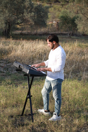 Man Plays The Musical Keyboard In The Countryside In Calabria Among Olive Treesの写真素材