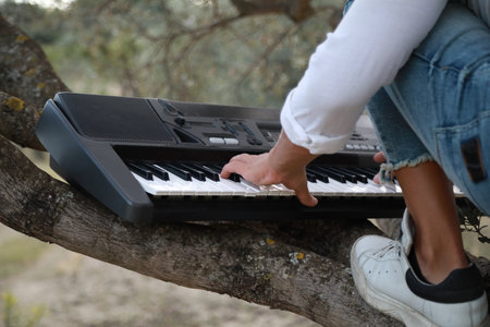 Boy Plays The Musical Keyboard On The Trunk Of A Treeの写真素材