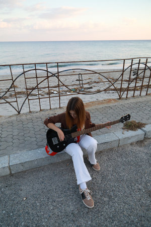 Girl Plays The Bass Instrument Sitting On The Step Near The Streetの写真素材