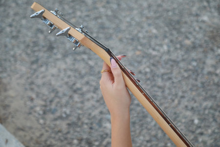 Girl Plays The Bass Instrument Sitting On The Step Near The Street At Evening