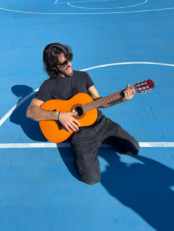 Long Hair Man Plays Guitar Outside In Blue Fieldの写真素材