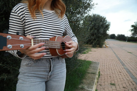 Girl Practices With Ukulele Musical Instrument In The Countryside During A Break