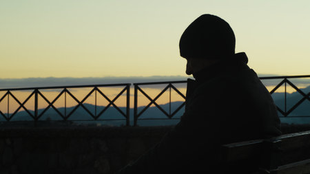 Silhouette Of A Man Sitting On Bench Watching Time Pass After Retirementの写真素材