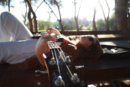 Girl Plays Bass Musical Instrument Lying On Table In Mountainsの写真素材
