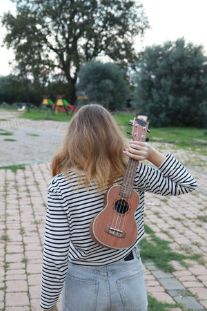 Artist Girl Plays Ukulele Musical Instrument Outside In Park