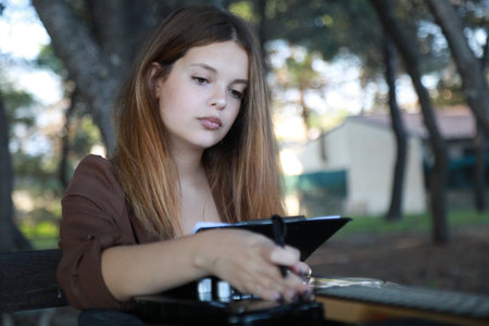 Girl Writes Music Notes On Sheet Music Sitting At The Park Table In The Nature