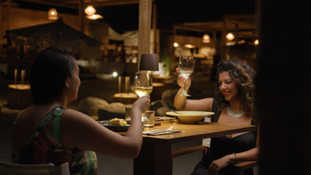 Two Women Cheering With A Glass Of Wine During A Dinner At The Luxury Resort